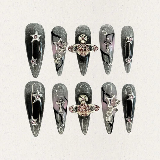 Celestial Voyage nail set features a shimmering gray base with celestial elements like stars and planets, adorned with intricate metallic and gemstone accents for a galactic aesthetic.