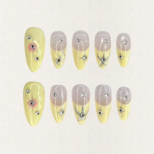 Lemon Gleam press-on nails with a soft gradient of yellow and nude shades, decorated with intricate silver linework and radiant starburst details, adding a touch of elegance and charm to your style.