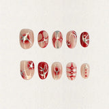 A press-on nail set featuring nude blush gradients with bold red patterns, celestial starbursts, and intricate white accents, creating an ethereal and romantic design.