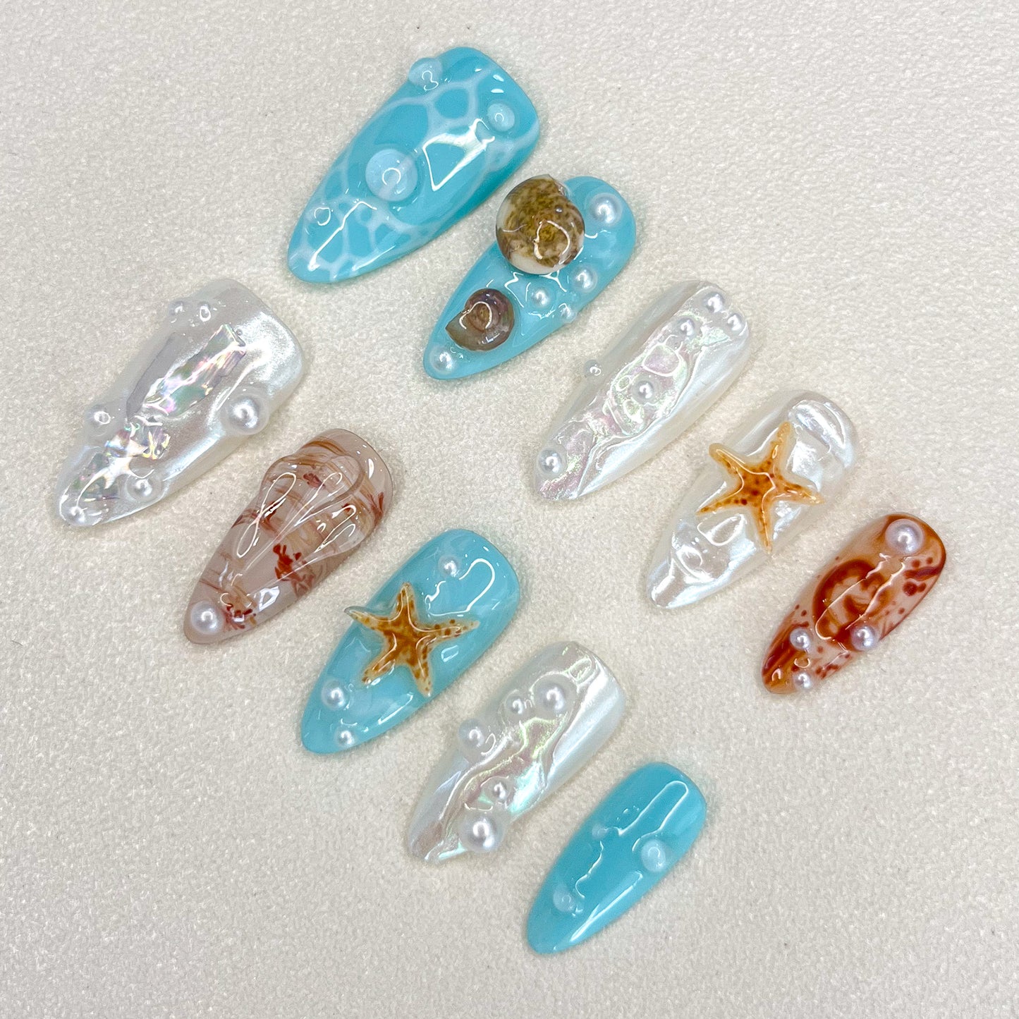 Ocean Pearls press-on nails featuring starfish, shells, and shimmering pearls for a chic, sea-inspired design.