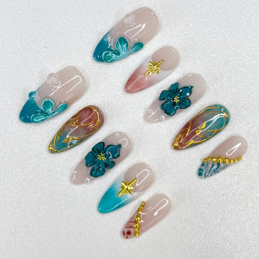 Tidal Serenity press-on nails with coastal-inspired tones, floral patterns, and golden details for a fresh and breezy aesthetic.