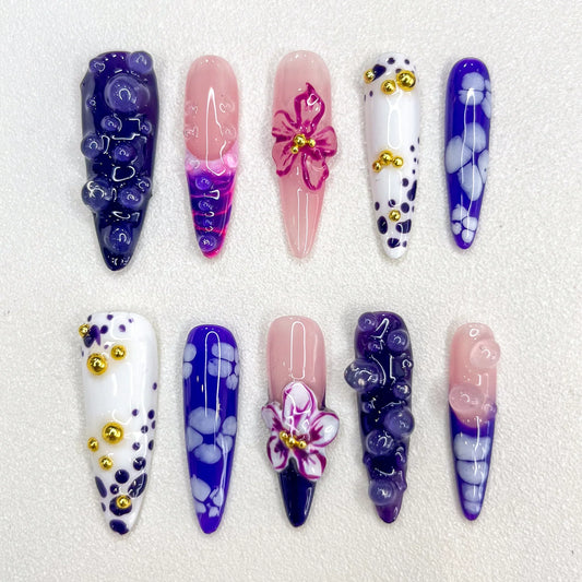 Amethyst Petals press-on nails with purple gradients, intricate floral designs, and golden accents that create a charming, luxurious look.