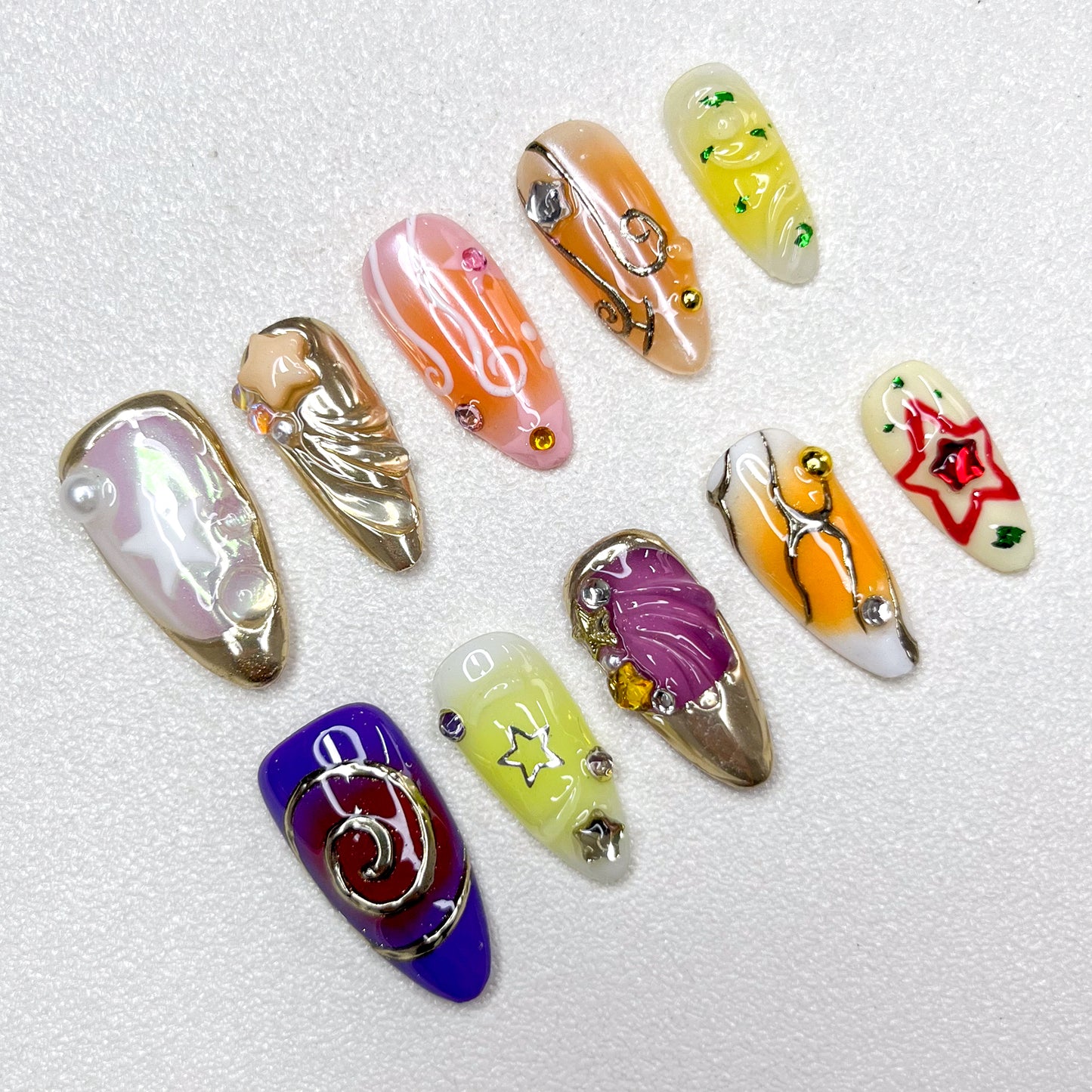 Galaxy-inspired press-on nails with star motifs, music notes, swirl designs, and metallic accents. Features shades of purple, gold, yellow, and orange, blended with celestial themes and 3D embellishments.
