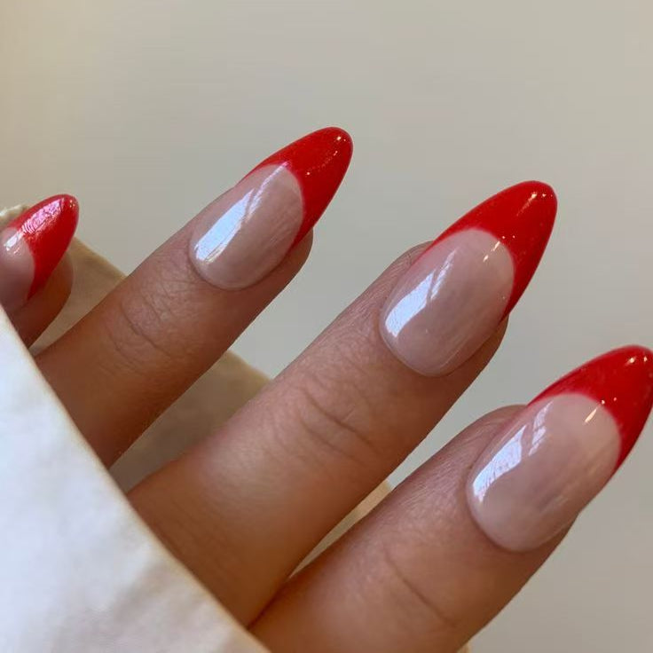 Crimson Chic nail set highlights vibrant red French tips on a neutral base, offering a timeless yet contemporary aesthetic.