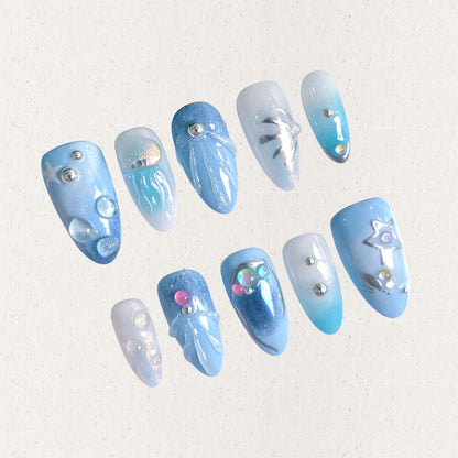 A set of press - on nails with light blue tones and intricate underwater designs, including jellyfish, bubbles, and starfish, embellished with shimmering details. The nails have a peaceful and magical look, great for beach trips or summer events.