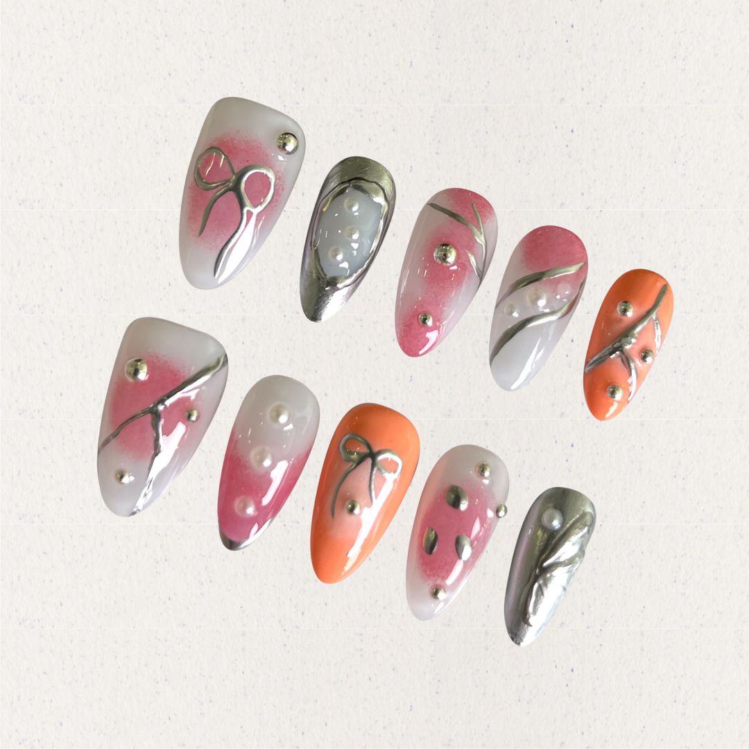 Press-on nails featuring delicate bows, metallic silver lines, and soft pink-to-orange gradients for a classy and sophisticated look.