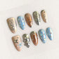 Floral Crystals nails display pastel shades with intricate pearl accents and floral designs, delivering a tender and romantic charm.