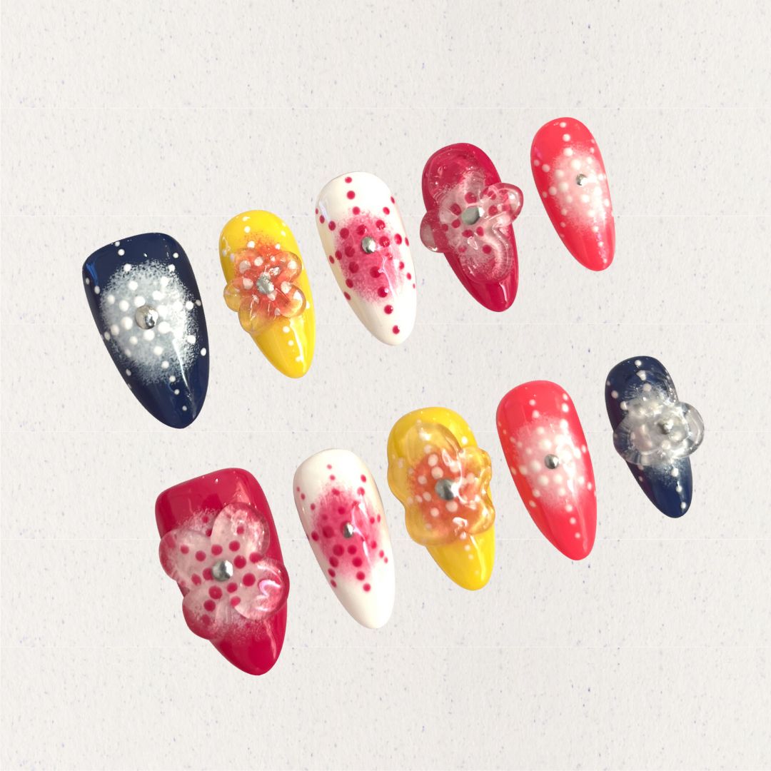 Bright press-on nails with dotted floral designs and translucent petals in warm, cheerful colors.