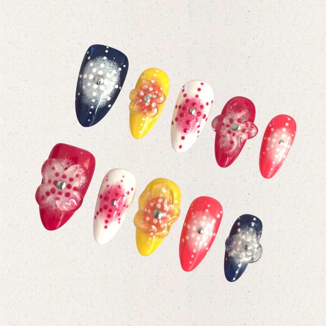 Bright press-on nails with dotted floral designs and translucent petals in warm, cheerful colors.