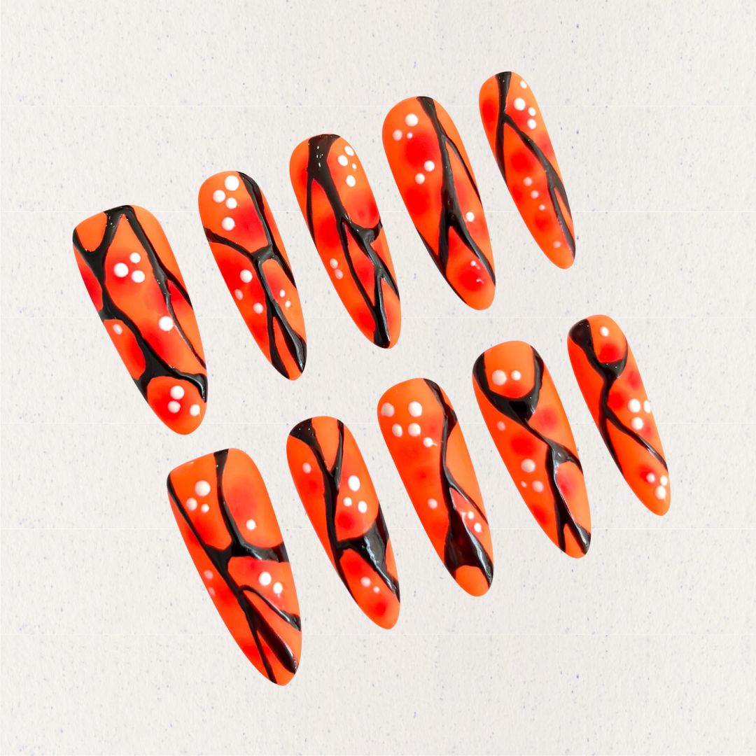 Orange and black press-on nails with coral-like patterns and white dot accents, delivering a natural and artistic appeal.