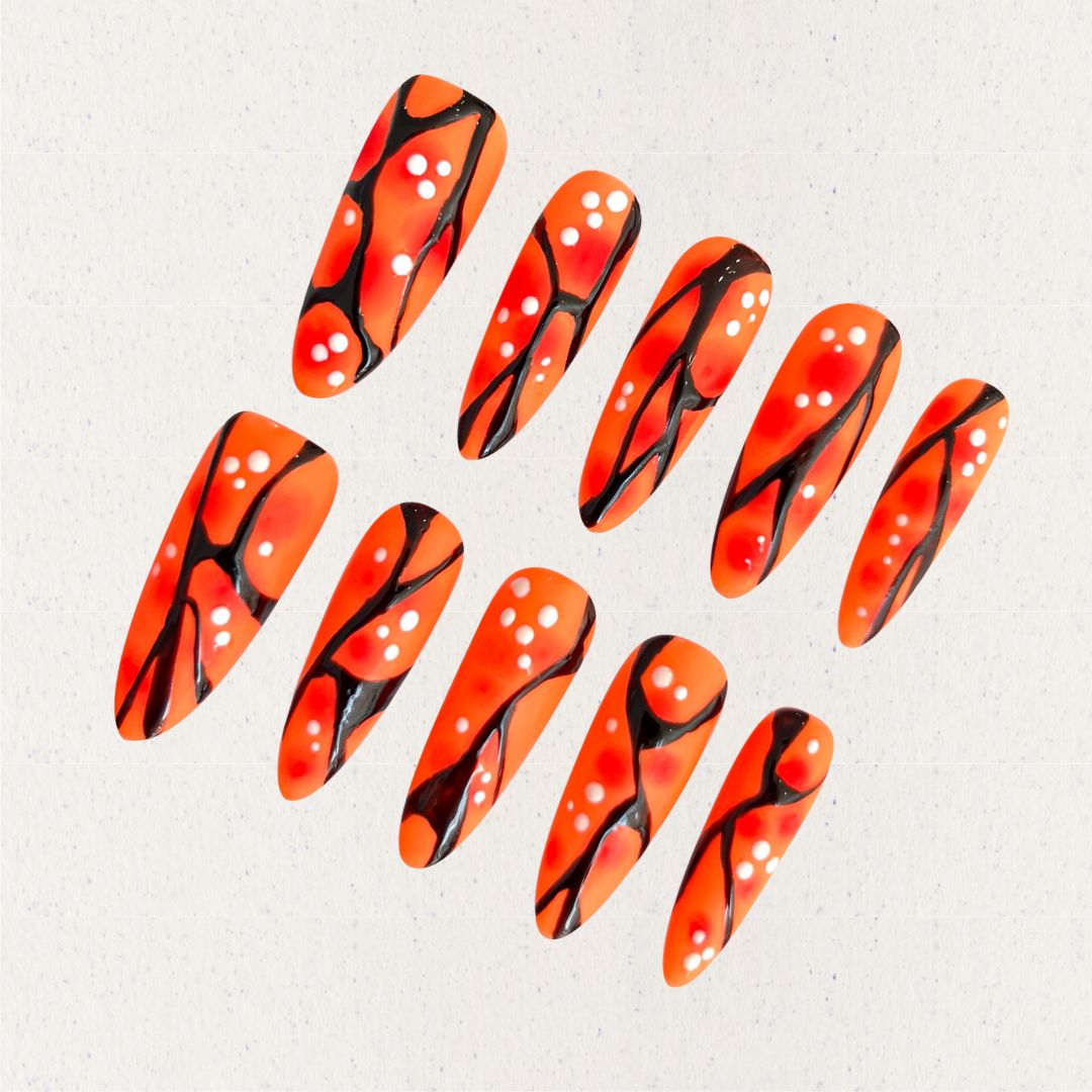 Orange and black press-on nails with coral-like patterns and white dot accents, delivering a natural and artistic appeal.