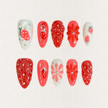 Elegant press-on nails inspired by strawberries, showcasing vibrant red textures and delicate white highlights for a charming touch.