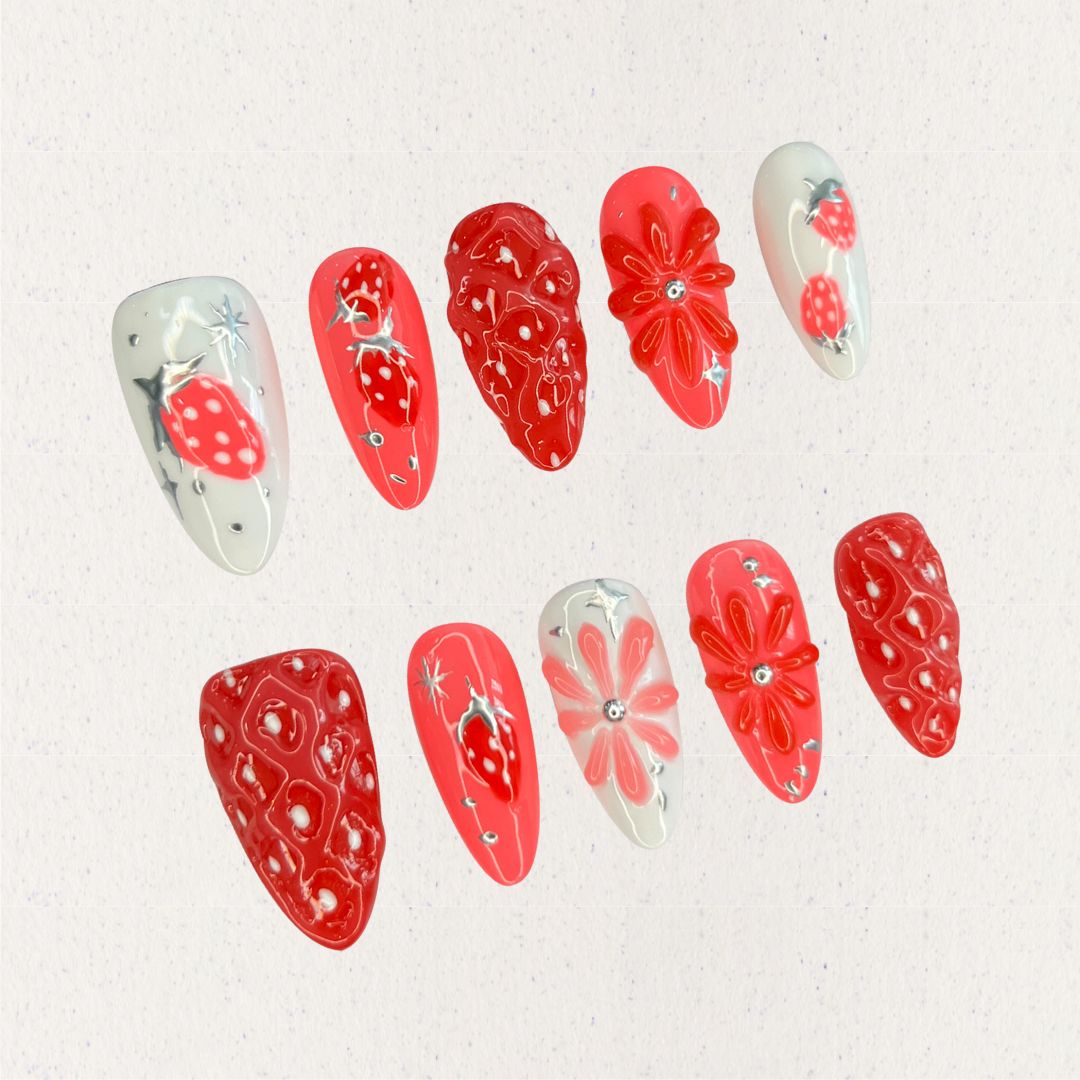 Elegant press-on nails inspired by strawberries, showcasing vibrant red textures and delicate white highlights for a charming touch.