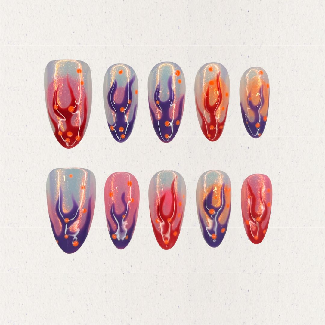 Dramatic press-on nails featuring flame-inspired designs in red, purple, and orange hues, creating a striking cosmic effect.