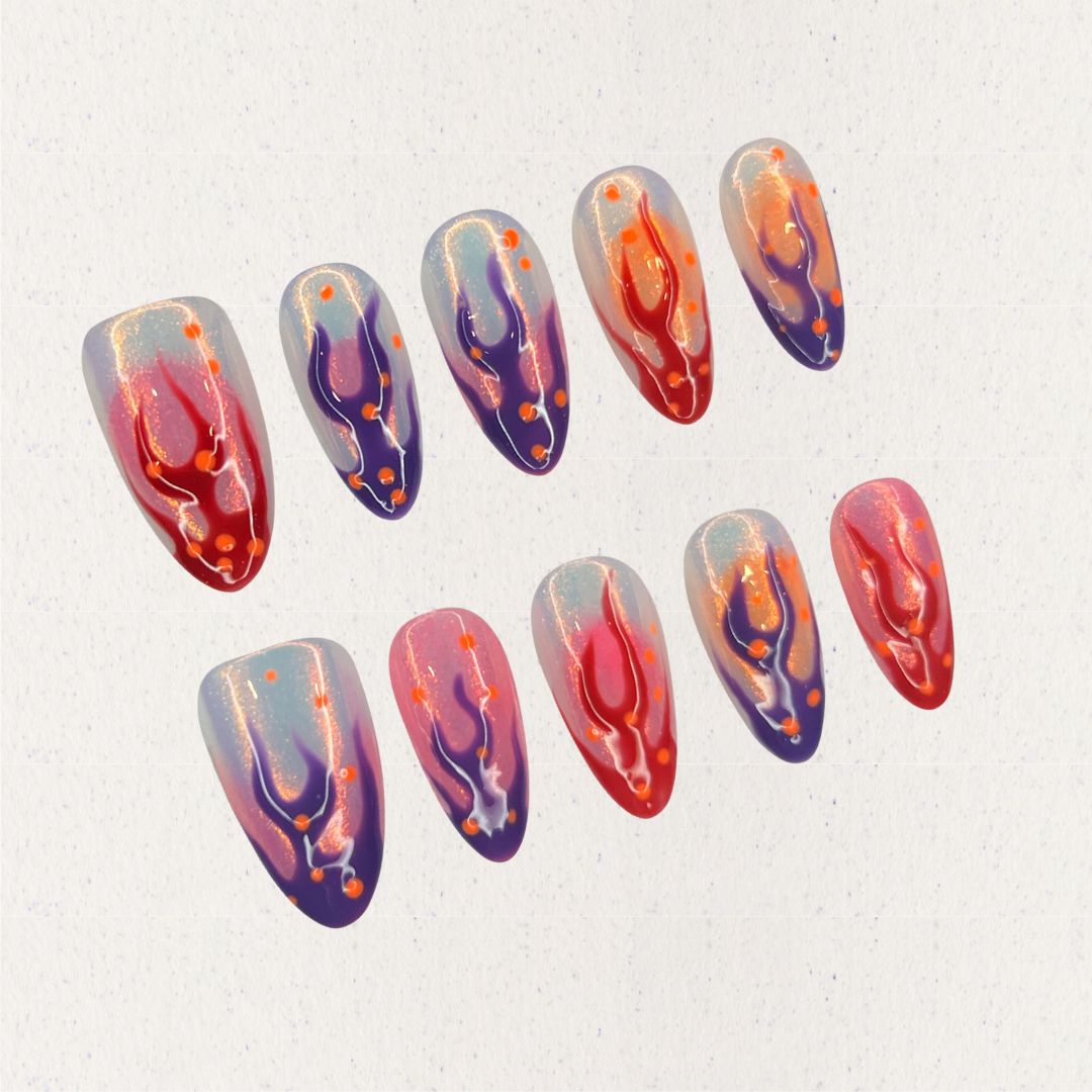 Dramatic press-on nails featuring flame-inspired designs in red, purple, and orange hues, creating a striking cosmic effect.