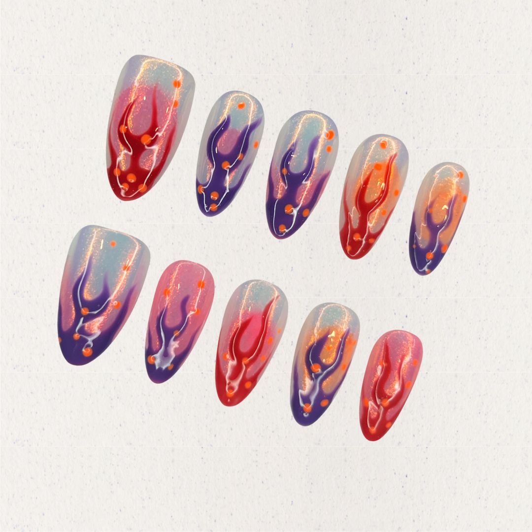 Dramatic press-on nails featuring flame-inspired designs in red, purple, and orange hues, creating a striking cosmic effect.