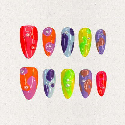 Colorful press-on nails with neon abstract patterns, featuring playful dots and fluid shapes in vivid hues.