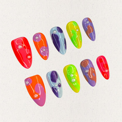 Colorful press-on nails with neon abstract patterns, featuring playful dots and fluid shapes in vivid hues.