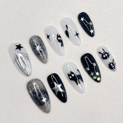 Cosmic Whispers press-on nails with star and constellation details in black, silver, and white for a celestial and dreamy look.