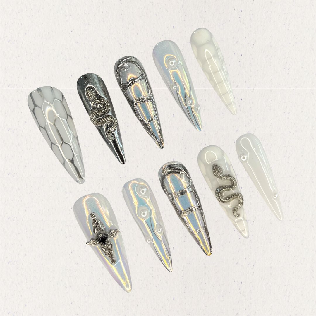 Silver Serpent highlights silver chrome nails with reptile-like textures, snake embellishments, and metallic cross details, creating a daring and mysterious look.