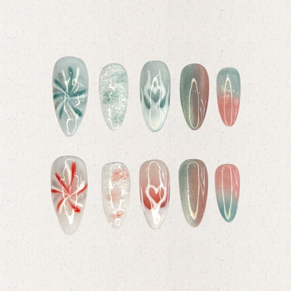 Ocean Reverie nail set combines aqua blues and coral pinks with wave patterns, soft floral motifs, and gradient fades, encapsulating the peaceful beauty of a coastal escape.