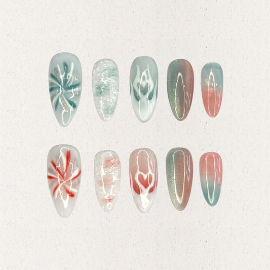 Ocean Reverie nail set combines aqua blues and coral pinks with wave patterns, soft floral motifs, and gradient fades, encapsulating the peaceful beauty of a coastal escape.