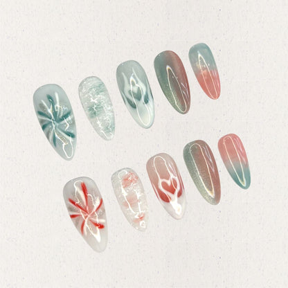 Ocean Reverie nail set combines aqua blues and coral pinks with wave patterns, soft floral motifs, and gradient fades, encapsulating the peaceful beauty of a coastal escape.