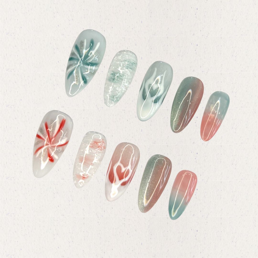 Ocean Reverie nail set combines aqua blues and coral pinks with wave patterns, soft floral motifs, and gradient fades, encapsulating the peaceful beauty of a coastal escape.