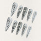 Liquid Metal Elegance features reflective silver press-on nails with flowing metallic patterns, creating a contemporary and bold aesthetic.