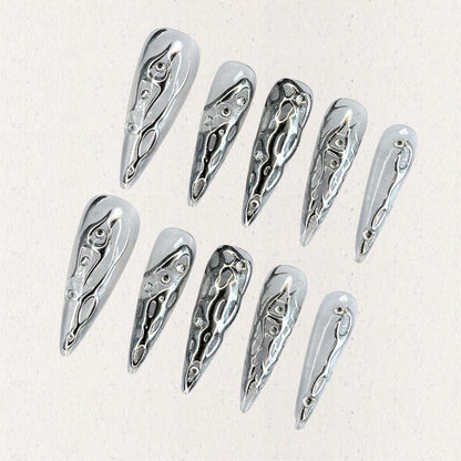 Liquid Metal Elegance features reflective silver press-on nails with flowing metallic patterns, creating a contemporary and bold aesthetic.