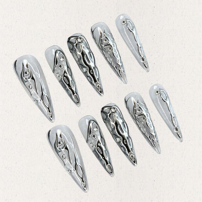 Liquid Metal Elegance features reflective silver press-on nails with flowing metallic patterns, creating a contemporary and bold aesthetic.