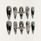 Celestial Voyage nail set features a shimmering gray base with celestial elements like stars and planets, adorned with intricate metallic and gemstone accents for a galactic aesthetic.