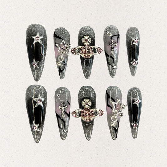 Celestial Voyage nail set features a shimmering gray base with celestial elements like stars and planets, adorned with intricate metallic and gemstone accents for a galactic aesthetic.