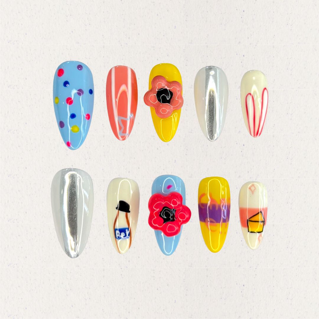 Playful Palette nail set showcases bold colors like blue, yellow, and coral with artistic patterns and fun motifs, capturing a lively and creative spirit.