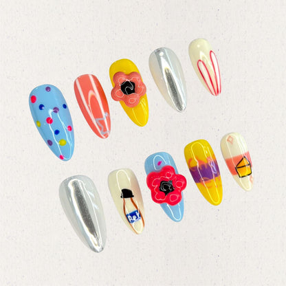 Playful Palette nail set showcases bold colors like blue, yellow, and coral with artistic patterns and fun motifs, capturing a lively and creative spirit.