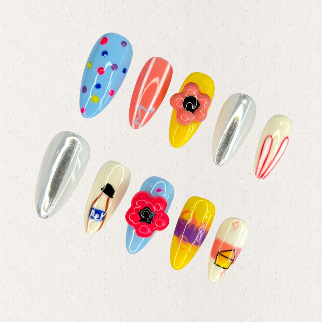 Playful Palette nail set showcases bold colors like blue, yellow, and coral with artistic patterns and fun motifs, capturing a lively and creative spirit.