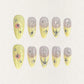 Lemon Gleam press-on nails with a soft gradient of yellow and nude shades, decorated with intricate silver linework and radiant starburst details, adding a touch of elegance and charm to your style.
