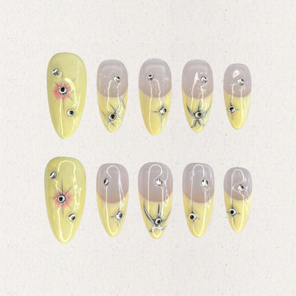 Lemon Gleam press-on nails with a soft gradient of yellow and nude shades, decorated with intricate silver linework and radiant starburst details, adding a touch of elegance and charm to your style.