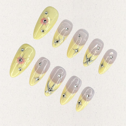 Lemon Gleam press-on nails with a soft gradient of yellow and nude shades, decorated with intricate silver linework and radiant starburst details, adding a touch of elegance and charm to your style.