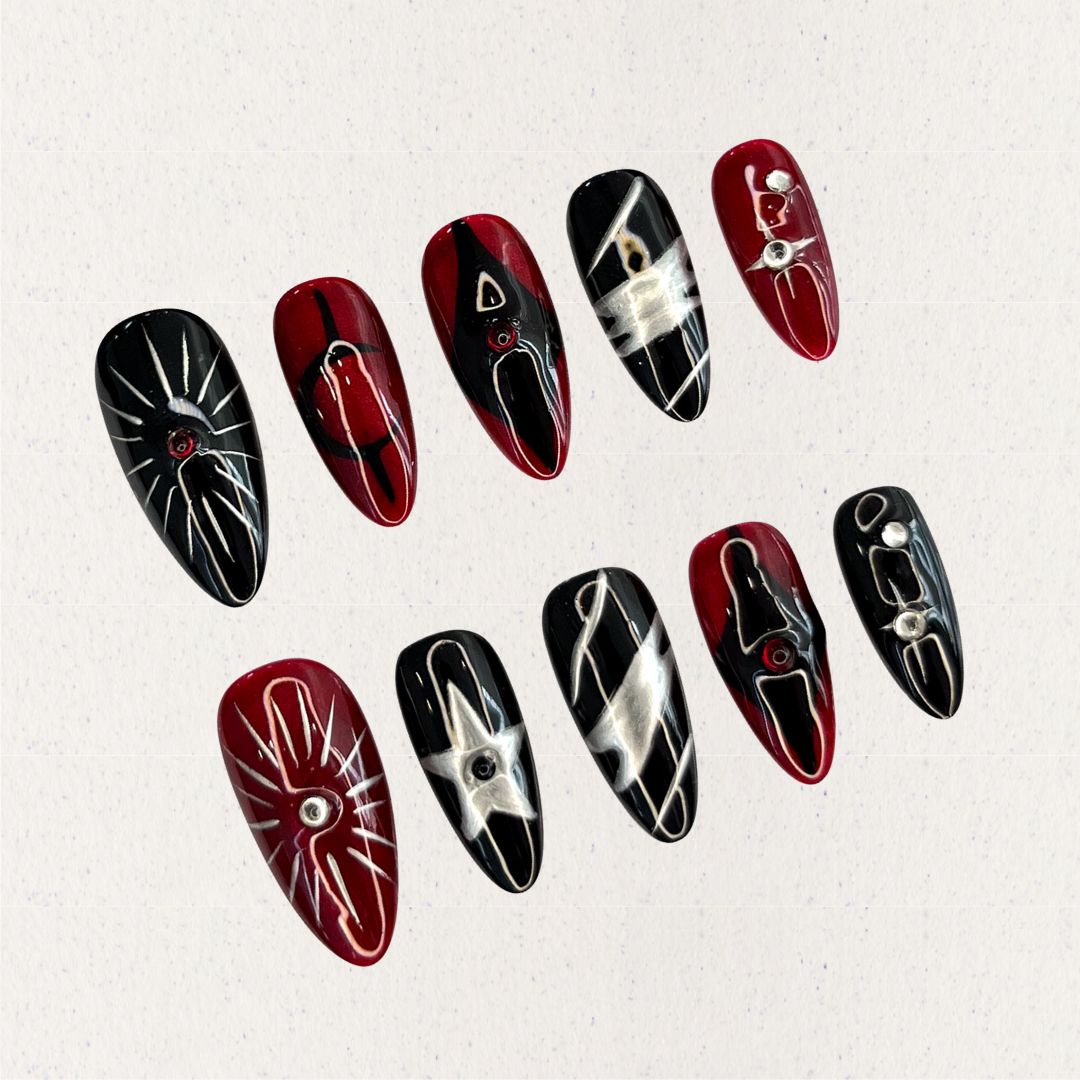 Crimson Eclipse nail set showcases a mix of black and red tones with silver highlights, celestial star designs, and geometric elements, perfect for a striking and dramatic look.