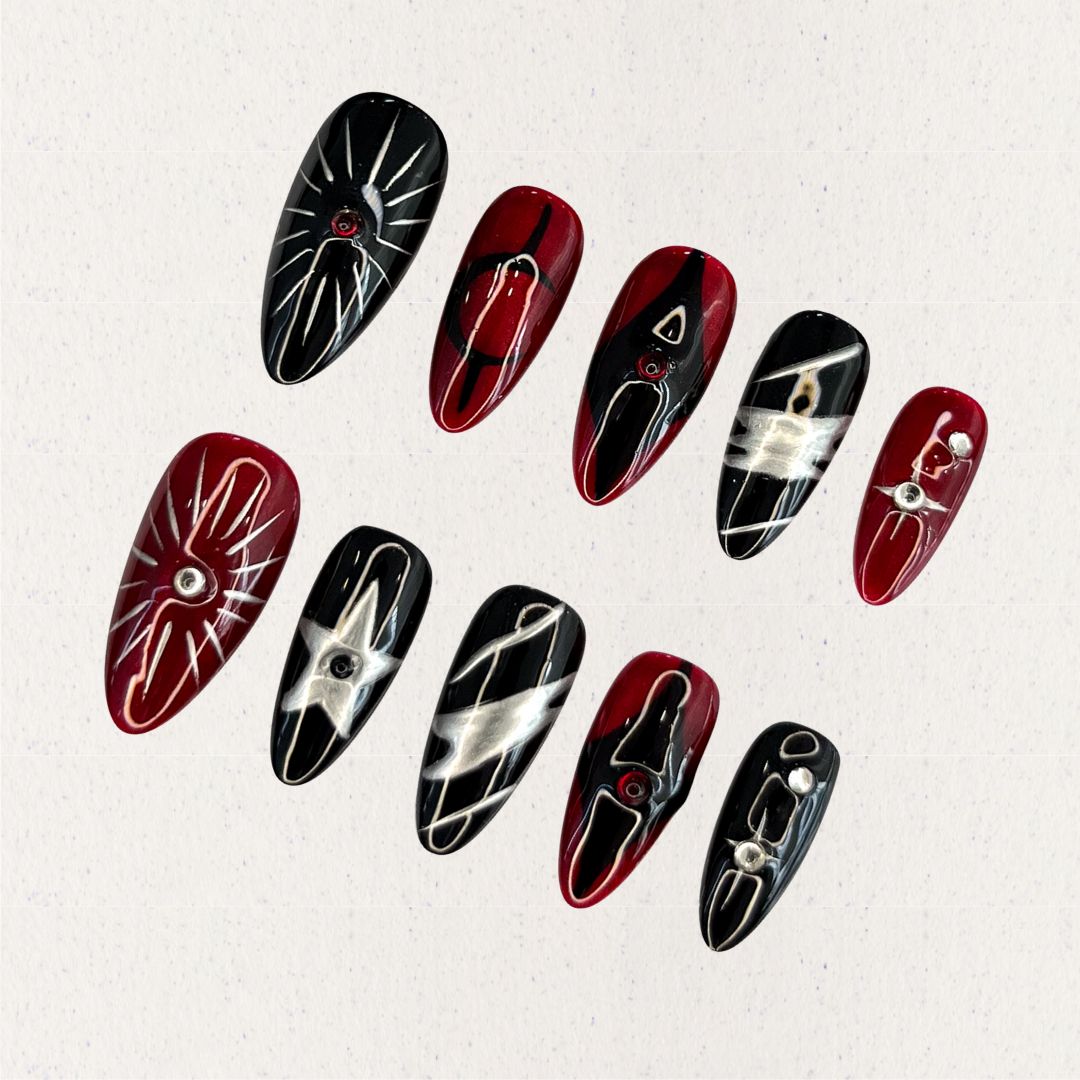 Crimson Eclipse nail set showcases a mix of black and red tones with silver highlights, celestial star designs, and geometric elements, perfect for a striking and dramatic look.