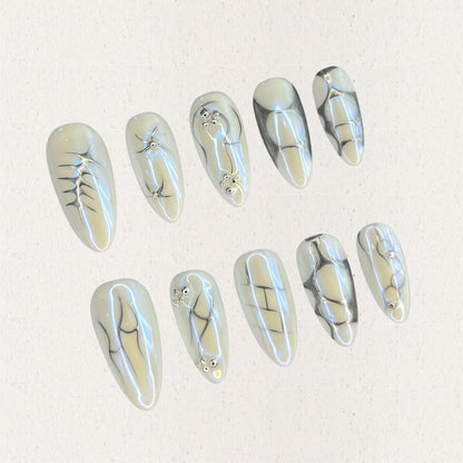 Fossil Radiance nail set features metallic pale shades with skeletal textures, geometric lines, and subtle shimmering accents, creating a sophisticated and enigmatic aesthetic.