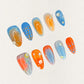 Oceanic Drift nail set includes vivid blue and orange hues with dot designs and glossy finishes, evoking the dynamic movement of the ocean.