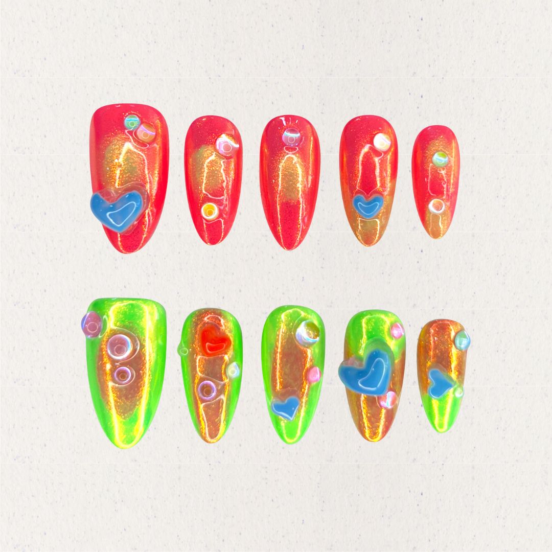 Solar Flares nail set features fiery red and neon green gradients with shimmering golden undertones, accented by 3D hearts and bubble-like embellishments. This vibrant design mirrors the dynamic beauty of solar eruptions and cosmic energy.