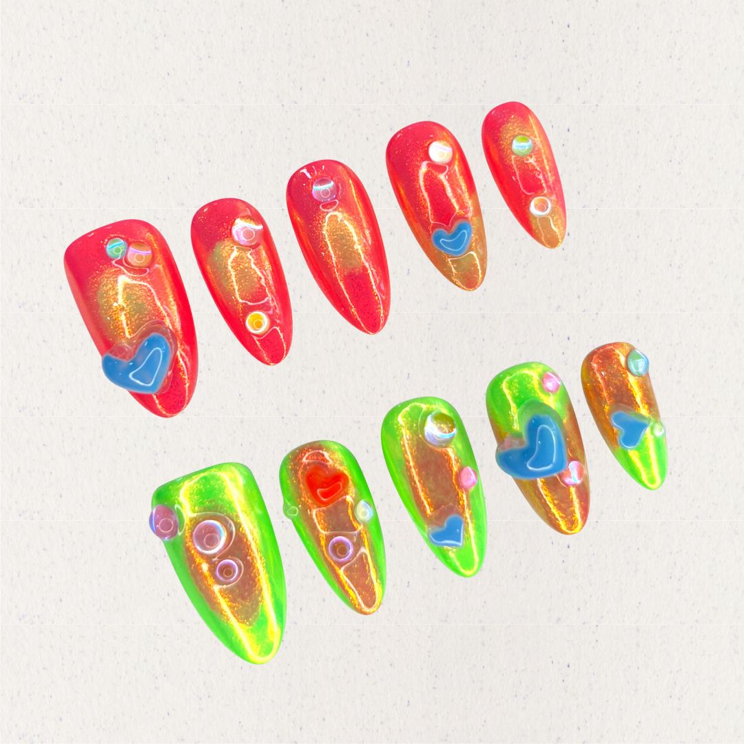 Solar Flares nail set features fiery red and neon green gradients with shimmering golden undertones, accented by 3D hearts and bubble-like embellishments. This vibrant design mirrors the dynamic beauty of solar eruptions and cosmic energy.