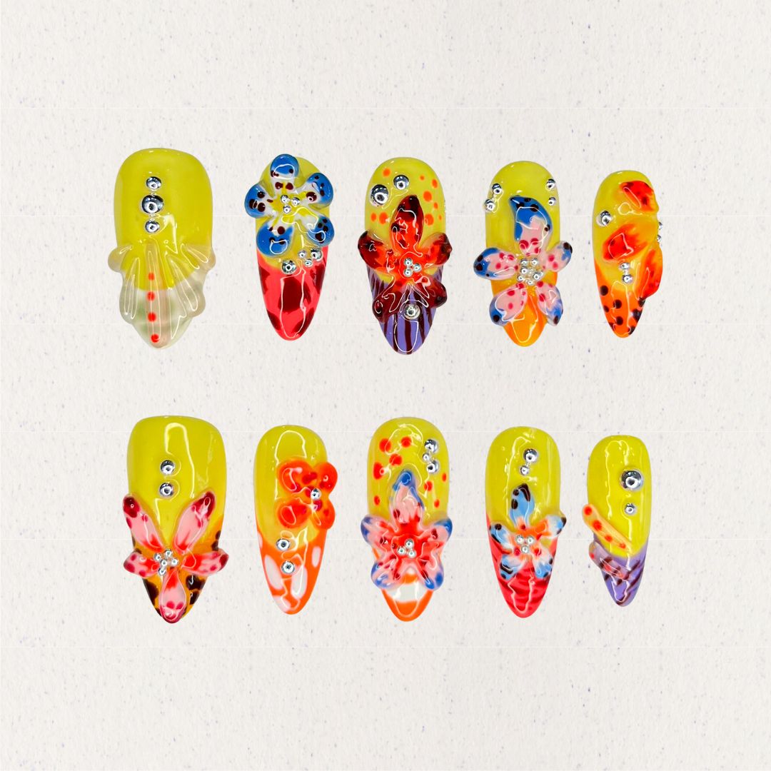 Blooming Fiesta nail set features a bright yellow base with vivid 3D flowers and rhinestones, creating a bold and celebratory floral design.