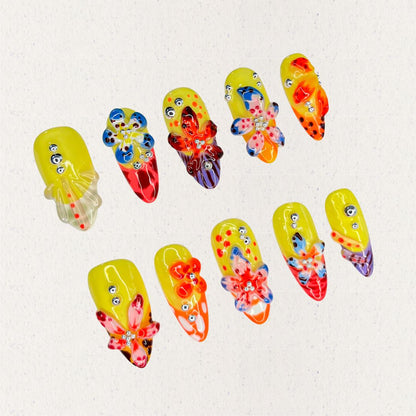 Blooming Fiesta nail set features a bright yellow base with vivid 3D flowers and rhinestones, creating a bold and celebratory floral design.