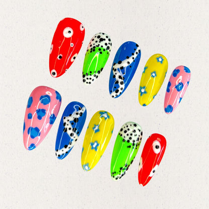 Galaxy Polka nail set takes inspiration from the playful and scattered look of a meteor shower, with bold colors like red, blue, and yellow adorned with polka dots and abstract celestial swirls. A lively design that feels like a colorful journey through the stars.