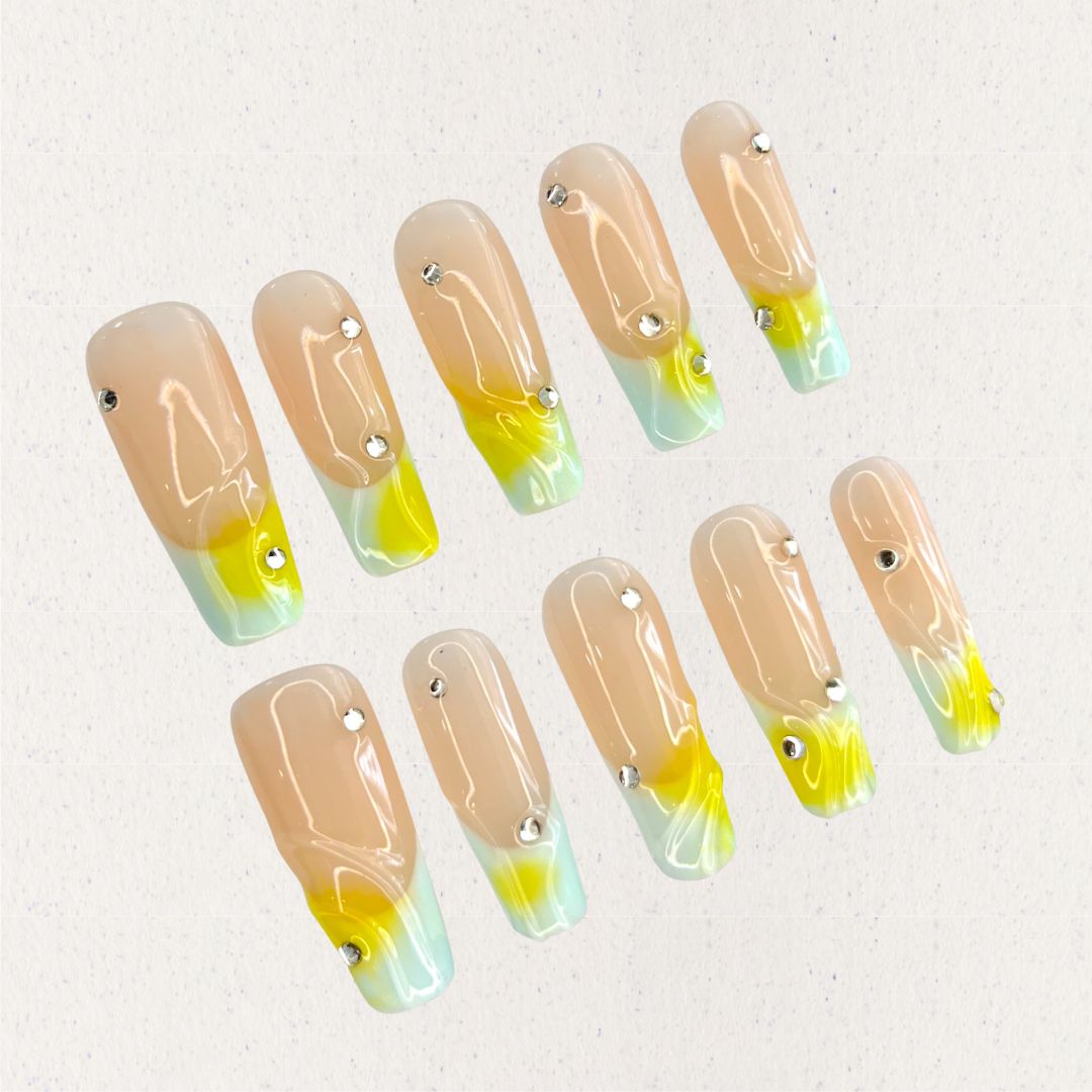 Morning Dew nail set features a subtle nude base with glowing yellow and green gradients, resembling the soft light of early morning. Accented with delicate crystal drops, this design evokes the freshness and purity of dew-drenched flowers at sunrise.