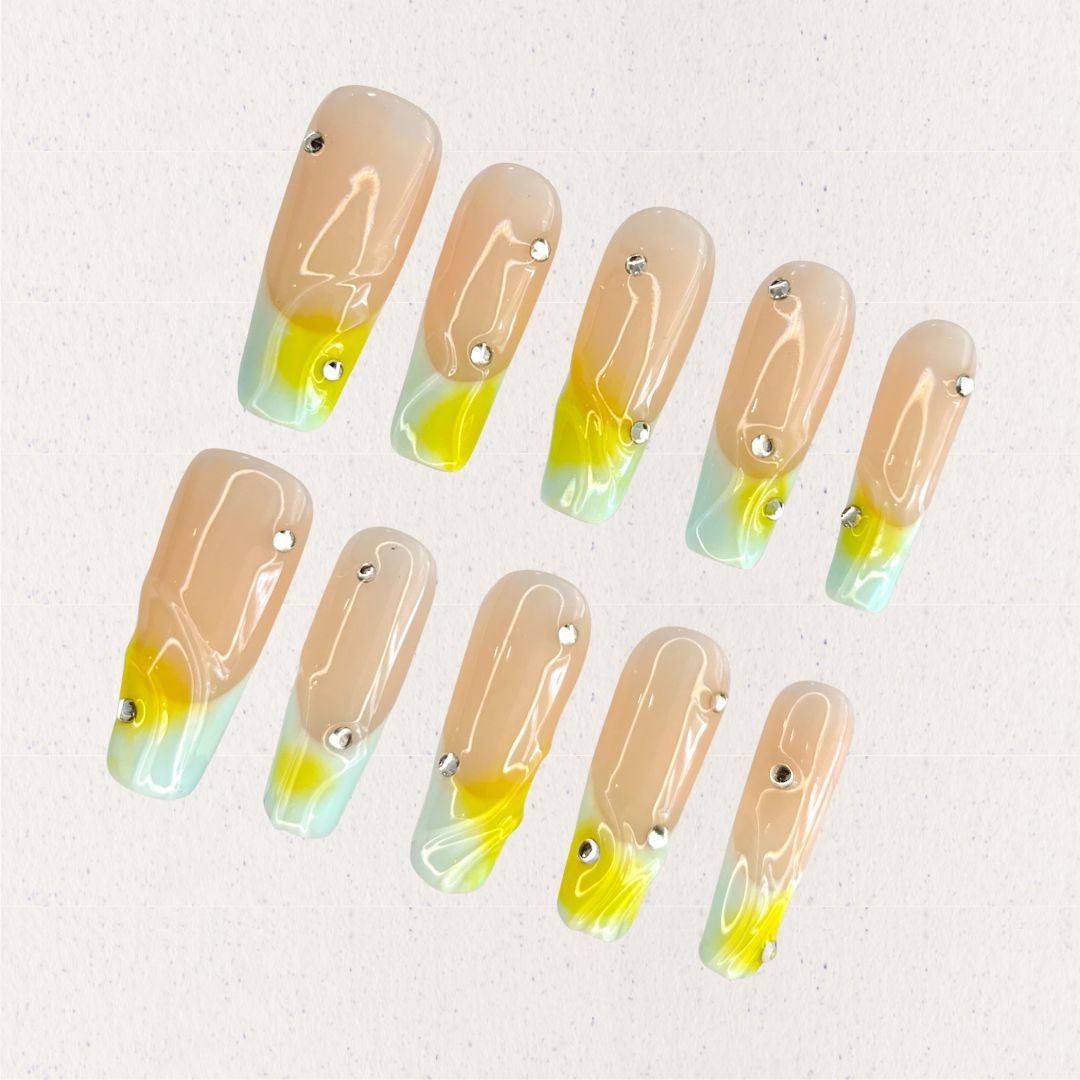 Morning Dew nail set features a subtle nude base with glowing yellow and green gradients, resembling the soft light of early morning. Accented with delicate crystal drops, this design evokes the freshness and purity of dew-drenched flowers at sunrise.